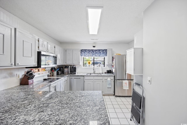 775 Plantation Dr Unit 28, Little River, SC 29566 - kitchen featuring appliances with stainless steel finishes, heating unit, decorative backsplash, light tile patterned floors, and light stone counters