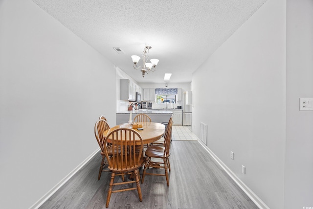 775 Plantation Dr Unit 28, Little River, SC 29566 - dining space featuring light wood-type flooring, a chandelier, and a textured ceiling