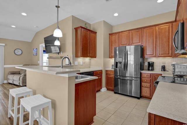 8855 Radcliff Dr NW Unit 53C, Calabash, NC 28467 - kitchen featuring stainless steel appliances, a peninsula, a kitchen bar, decorative backsplash, and a sink