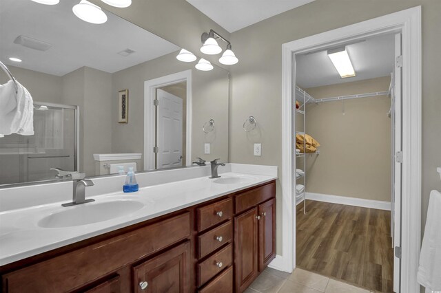 8855 Radcliff Dr NW Unit 53C, Calabash, NC 28467 - bathroom featuring a walk in closet, double vanity, a stall shower, tile patterned floors, and baseboards