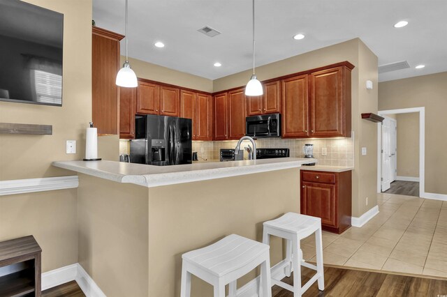 8855 Radcliff Dr NW Unit 53C, Calabash, NC 28467 - kitchen featuring black appliances, decorative backsplash, a breakfast bar, decorative light fixtures, and recessed lighting