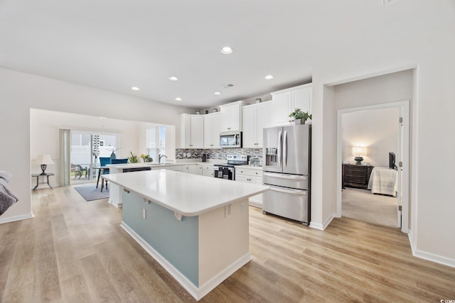 924 Sorano St, Myrtle Beach, SC 29579 - kitchen featuring stainless steel appliances, light countertops, a center island, light wood-style floors, and white cabinetry