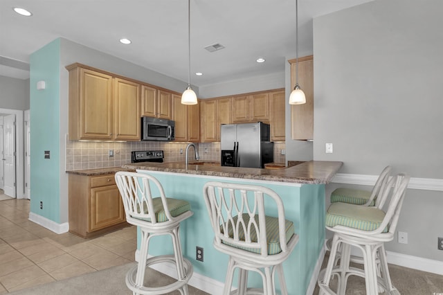8855 Radcliff Dr NW Unit 53D, Calabash, NC 28467 - kitchen featuring stainless steel appliances, backsplash, a breakfast bar area, light tile patterned floors, and a peninsula