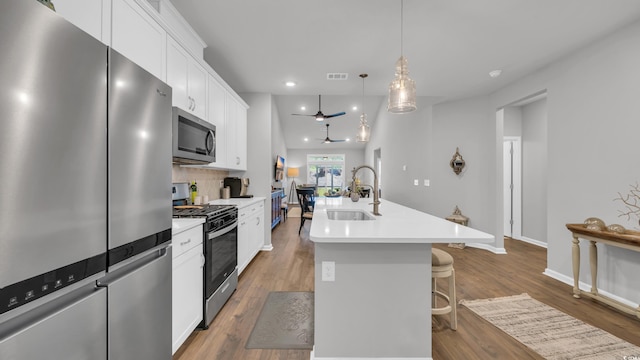 4053 Taranto Loop Unit C, Myrtle Beach, SC 29579 - kitchen with appliances with stainless steel finishes, an island with sink, white cabinetry, a kitchen bar, and wood finished floors