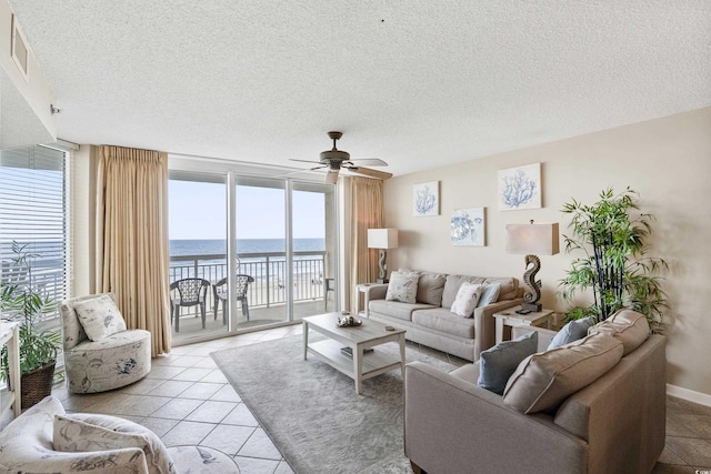 1625 S Ocean Blvd Unit 309, North Myrtle Beach, SC 29582 - living area featuring a water view, ceiling fan, a textured ceiling, light tile patterned flooring, and floor to ceiling windows