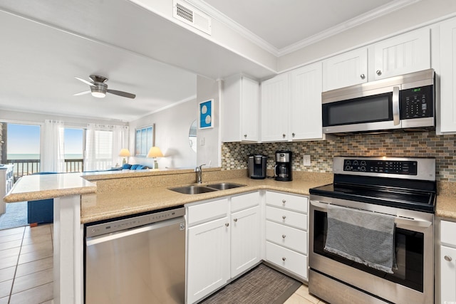 208 Ocean Blvd N Unit 226, North Myrtle Beach, SC 29582 - kitchen featuring appliances with stainless steel finishes, a peninsula, ornamental molding, decorative backsplash, and white cabinetry
