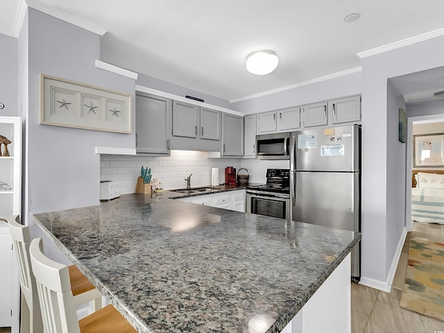1310 N Waccamaw Dr Unit 208, Garden City Beach, SC 29576 - kitchen featuring appliances with stainless steel finishes, a sink, a peninsula, gray cabinets, and decorative backsplash