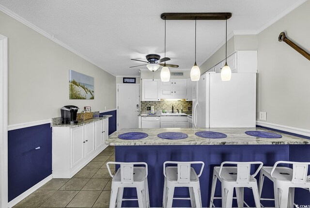 9660 Shore Dr Unit 208, Myrtle Beach, SC 29572 - kitchen with white appliances, a ceiling fan, white cabinets, a peninsula, and a kitchen bar