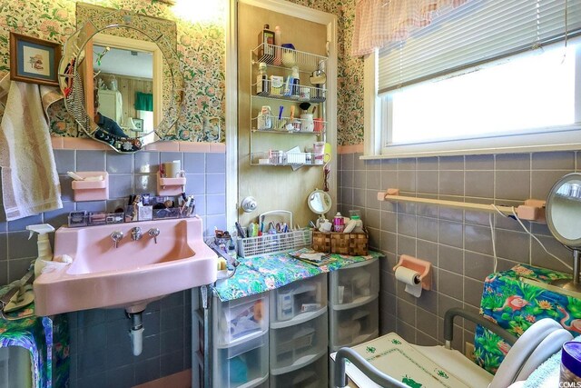 404 13th Ave S, Myrtle Beach, SC 29577 - bathroom featuring tile walls, wallpapered walls, a wainscoted wall, and a sink