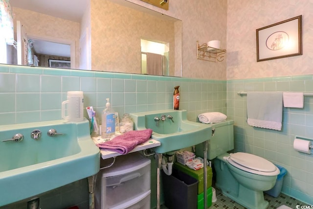404 13th Ave S, Myrtle Beach, SC 29577 - bathroom with tile walls, wallpapered walls, toilet, a sink, and wainscoting