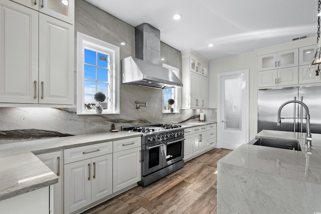 208 W Palms Dr, Myrtle Beach, SC 29579 - kitchen featuring double oven range, wall chimney range hood, a sink, white cabinetry, and light wood-type flooring