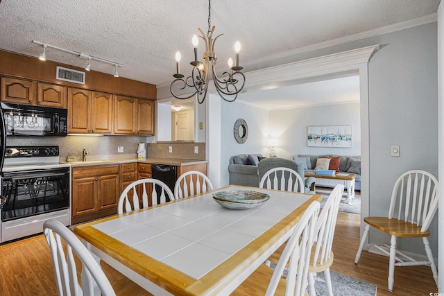 5905 S Kings Hwy Unit A518, Myrtle Beach, SC 29575 - dining space featuring light wood-type flooring, a chandelier, track lighting, crown molding, and a textured ceiling