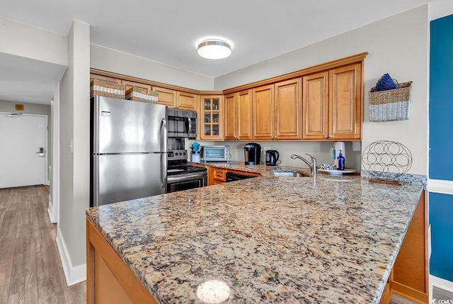 2500 N Ocean Blvd Unit 1102, Myrtle Beach, SC 29577 - kitchen featuring stainless steel appliances, a peninsula, brown cabinets, light stone countertops, and glass insert cabinets