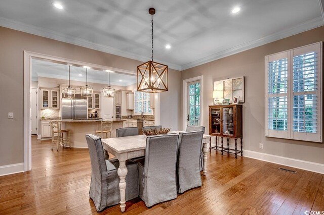 9 Winnowing Way, Pawleys Island, SC 29585 - dining area featuring wood finished floors, crown molding, recessed lighting, a chandelier, and baseboards