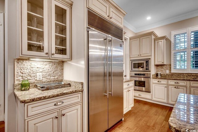 9 Winnowing Way, Pawleys Island, SC 29585 - kitchen featuring built in appliances, crown molding, light wood finished floors, cream cabinetry, and backsplash