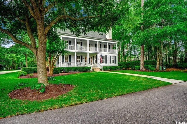 9 Winnowing Way, Pawleys Island, SC 29585 - view of front of home featuring covered porch, a chimney, a front lawn, a balcony, and ceiling fan