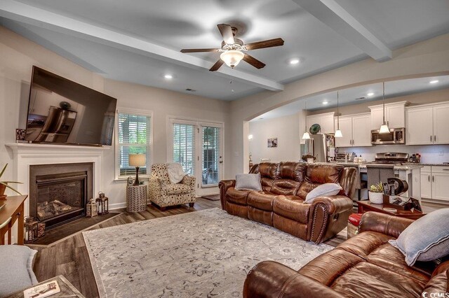 3091 Viceroy Loop, Little River, SC 29566 - living area with beamed ceiling, ceiling fan, dark wood-style flooring, arched walkways, and a fireplace with flush hearth