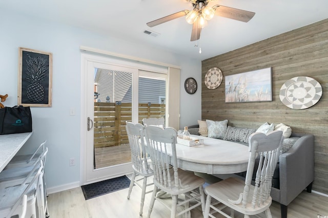 4307 Beverly Ct, North Myrtle Beach, SC 29582 - dining area with wooden walls, a ceiling fan, light wood-style flooring, an accent wall, and baseboards