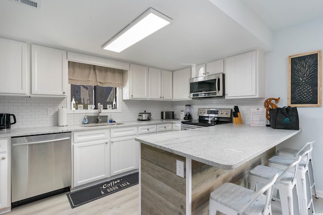 4307 Beverly Ct, North Myrtle Beach, SC 29582 - kitchen with stainless steel appliances, backsplash, a sink, a peninsula, and white cabinetry