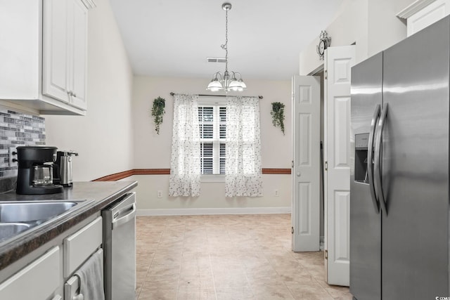 176 Whispering Oaks Dr, Longs, SC 29568 - kitchen with appliances with stainless steel finishes, dark countertops, white cabinets, tasteful backsplash, and a chandelier