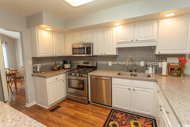 18 Pine Valley Ln, Surfside Beach, SC 29575 - kitchen featuring appliances with stainless steel finishes, a sink, wood finished floors, white cabinetry, and tasteful backsplash