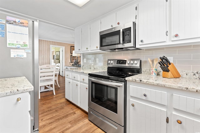 161 Easy St, Garden City Beach, SC 29576 - kitchen featuring appliances with stainless steel finishes, decorative backsplash, light wood finished floors, white cabinetry, and light stone countertops