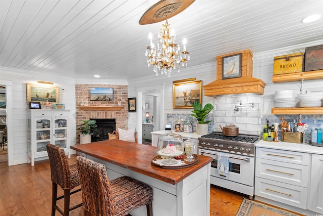309 Sunset Trl, Myrtle Beach, SC 29577 - kitchen with stainless steel stove, a chandelier, a fireplace, wood finished floors, and crown molding