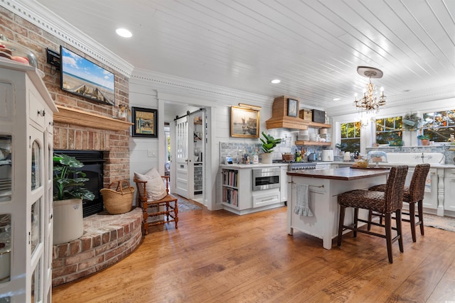 309 Sunset Trl, Myrtle Beach, SC 29577 - kitchen with open shelves, light wood-style flooring, a chandelier, a kitchen bar, and ornamental molding