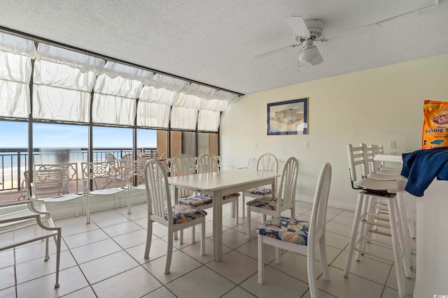 4000 N Ocean Blvd Unit 506, North Myrtle Beach, SC 29582 - tiled dining space with a ceiling fan, a water view, a textured ceiling, and baseboards