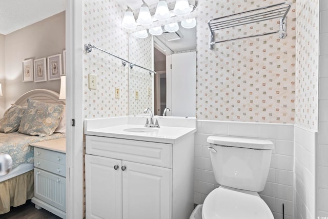 4000 N Ocean Blvd Unit 506, North Myrtle Beach, SC 29582 - bathroom with vanity, toilet, wainscoting, wallpapered walls, and tile walls