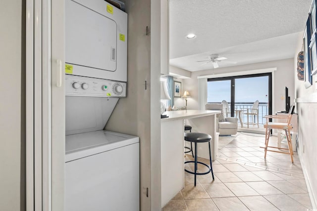 4000 N Ocean Blvd Unit 506, North Myrtle Beach, SC 29582 - laundry room with estacked washer and dryer, a ceiling fan, light tile patterned floors, and a textured ceiling