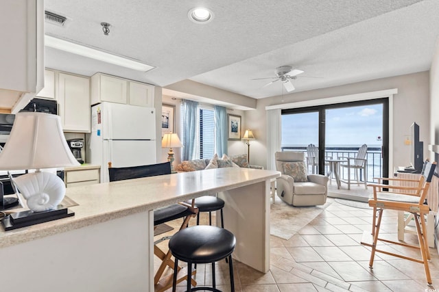 4000 N Ocean Blvd Unit 506, North Myrtle Beach, SC 29582 - kitchen with freestanding refrigerator, a kitchen breakfast bar, ceiling fan, light countertops, and black microwave