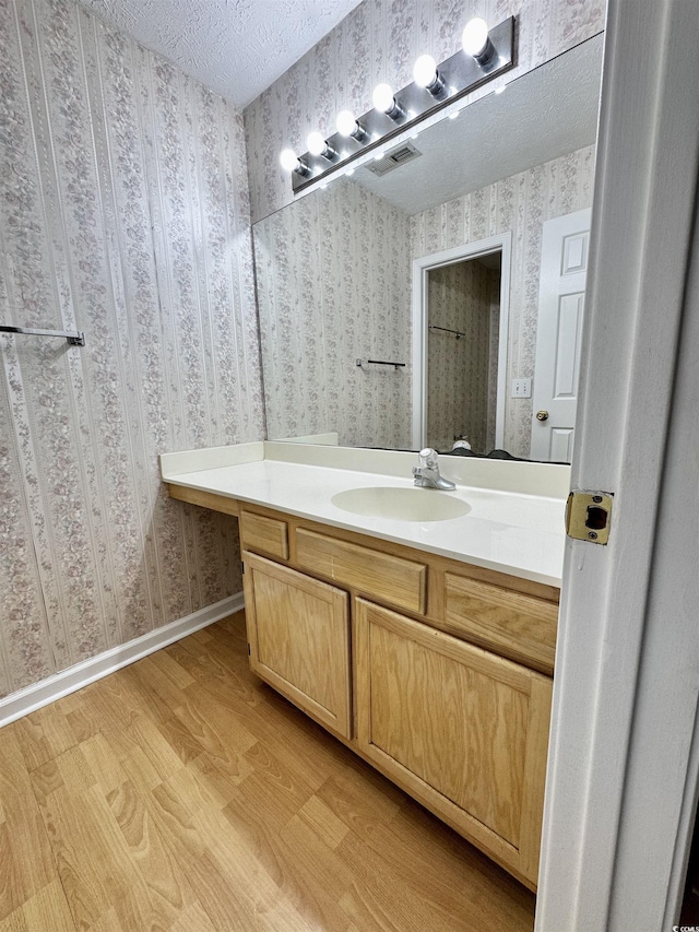 665 Tupelo Ln Unit 17-D, Longs, SC 29568 - bathroom with wallpapered walls, wood finished floors, vanity, a textured ceiling, and baseboards