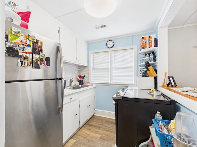 401 17th Ave S, North Myrtle Beach, SC 29582 - kitchen with freestanding refrigerator, a sink, light wood finished floors, crown molding, and white cabinets
