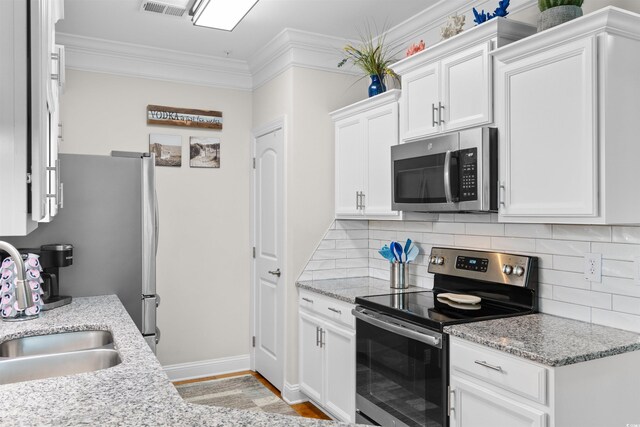 186 Ella Kinley Cir Unit 101, Myrtle Beach, SC 29588 - kitchen with appliances with stainless steel finishes, tasteful backsplash, white cabinetry, ornamental molding, and light wood-style floors