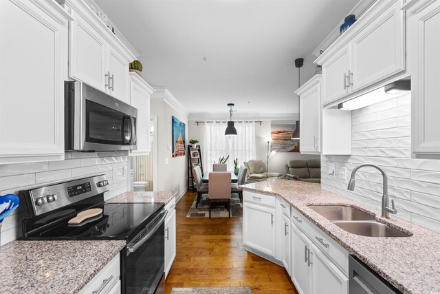 186 Ella Kinley Cir Unit 101, Myrtle Beach, SC 29588 - kitchen featuring appliances with stainless steel finishes, a sink, white cabinets, decorative backsplash, and ornamental molding