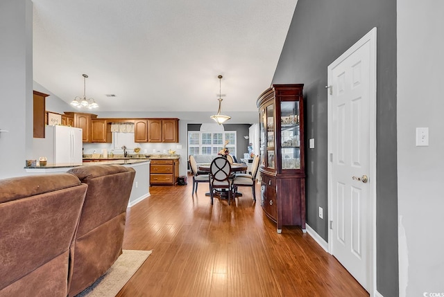 156 Hummingbird Ct, Myrtle Beach, SC 29579 - kitchen featuring freestanding refrigerator, vaulted ceiling, a chandelier, wood finished floors, and brown cabinetry