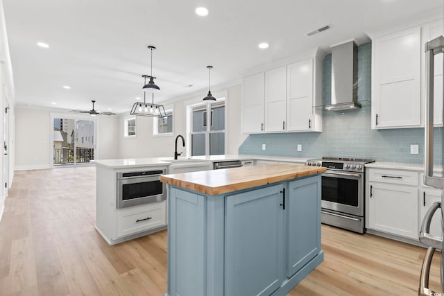 4617 Hedrick St, North Myrtle Beach, SC 29582 - kitchen with stainless steel range with gas cooktop, wood counters, wall chimney exhaust hood, a peninsula, and a center island