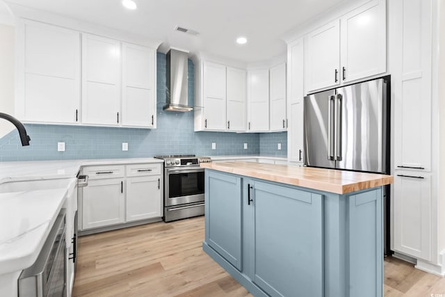 4617 Hedrick St, North Myrtle Beach, SC 29582 - kitchen with wall chimney exhaust hood, appliances with stainless steel finishes, butcher block counters, light wood-style flooring, and a center island