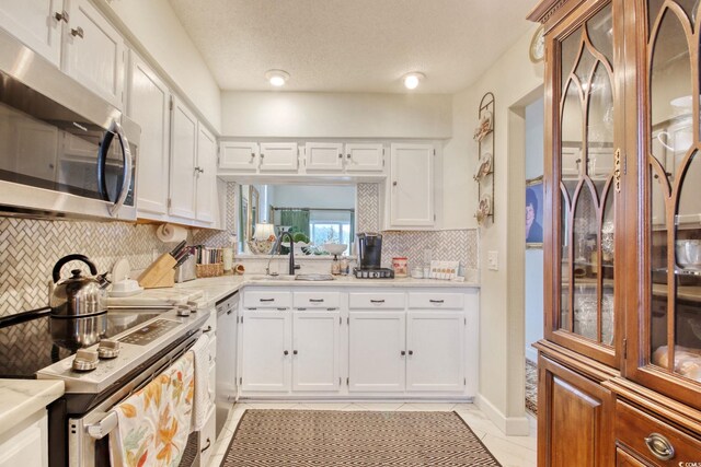 4396 Baldwin Ave Unit 1, Little River, SC 29566 - kitchen with appliances with stainless steel finishes, a sink, tasteful backsplash, white cabinets, and light tile patterned floors