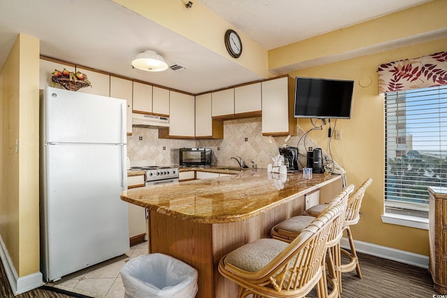 1605 S Ocean Blvd Unit 204, Myrtle Beach, SC 29577 - kitchen with white appliances, under cabinet range hood, a peninsula, tasteful backsplash, and baseboards