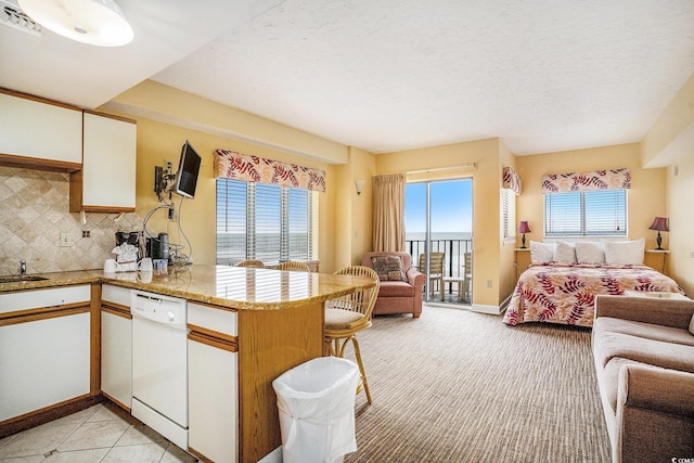 1605 S Ocean Blvd Unit 204, Myrtle Beach, SC 29577 - kitchen featuring open floor plan, white dishwasher, a peninsula, white cabinets, and backsplash