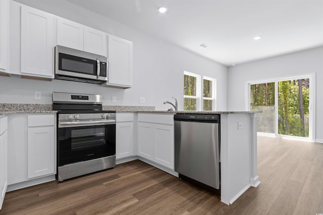 786 NW Palm Frond Way Unit 51, Calabash, NC 28467 - kitchen with stainless steel appliances, a peninsula, dark wood-style floors, white cabinetry, and recessed lighting