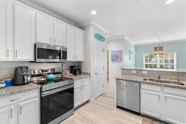 411 Mahogany Dr Unit 101, Murrells Inlet, SC 29576 - kitchen featuring stainless steel appliances, a sink, light wood-type flooring, ornamental molding, and white cabinetry