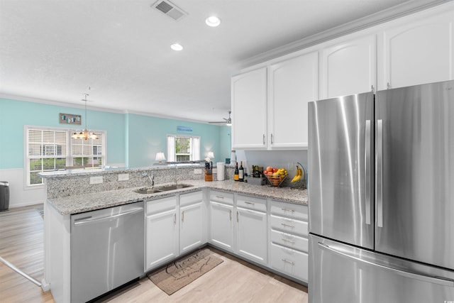 411 Mahogany Dr Unit 101, Murrells Inlet, SC 29576 - kitchen featuring appliances with stainless steel finishes, a sink, a peninsula, light wood-style floors, and white cabinets