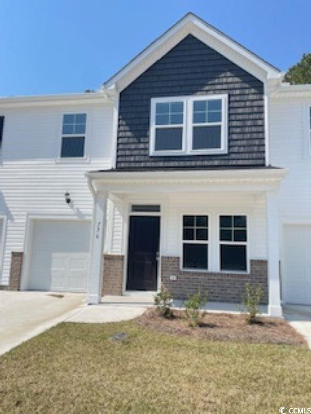 776 NW Palm Frond Way Unit 55, Calabash, NC 28467 - view of front of property with a garage, brick siding, covered porch, driveway, and a front yard