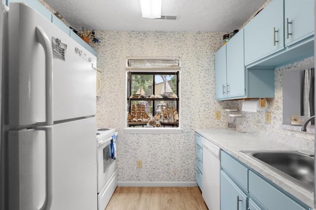 614 15th Ave S Unit 41, Surfside Beach, SC 29575 - kitchen featuring blue cabinets, white appliances, wallpapered walls, light wood-style flooring, and a textured ceiling