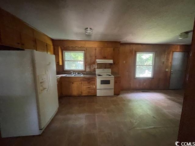 41 Harmon St, Hemingway, SC 29554 - kitchen featuring white appliances, under cabinet range hood, healthy amount of natural light, wooden walls, and brown cabinetry