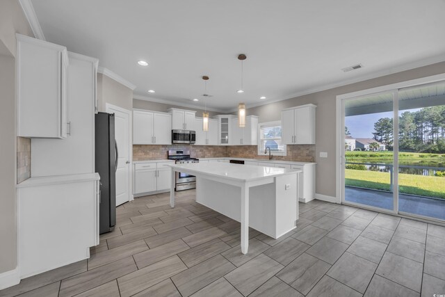 5621 Camilla Ct, Myrtle Beach, SC 29579 - kitchen featuring appliances with stainless steel finishes, backsplash, a kitchen breakfast bar, a center island, and ornamental molding
