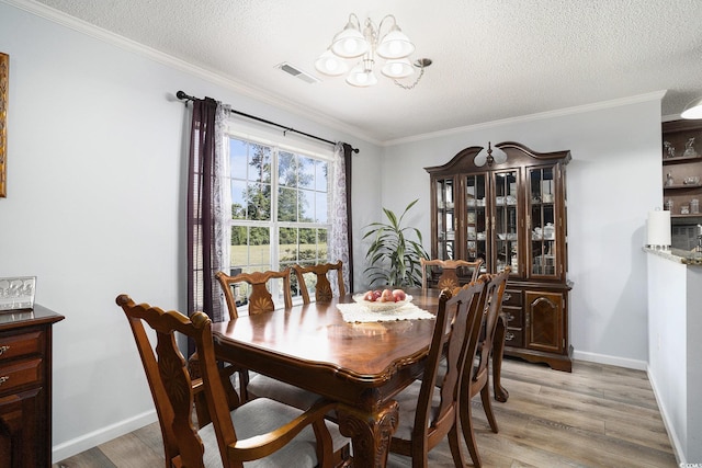 2981 Victor Rd, Longs, SC 29568 - dining area with a chandelier, light wood-style floors, a textured ceiling, ornamental molding, and baseboards